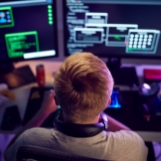 male teenage hacker sitting in front of computer